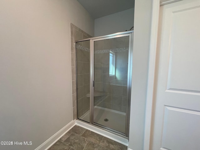 bathroom with baseboards and a shower stall