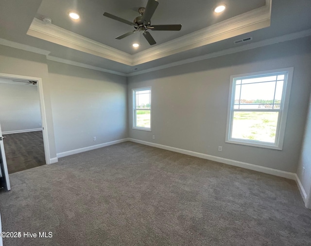 unfurnished bedroom with crown molding, dark carpet, visible vents, a raised ceiling, and baseboards