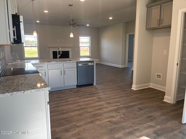kitchen with ceiling fan, dishwasher, a sink, open floor plan, and baseboards