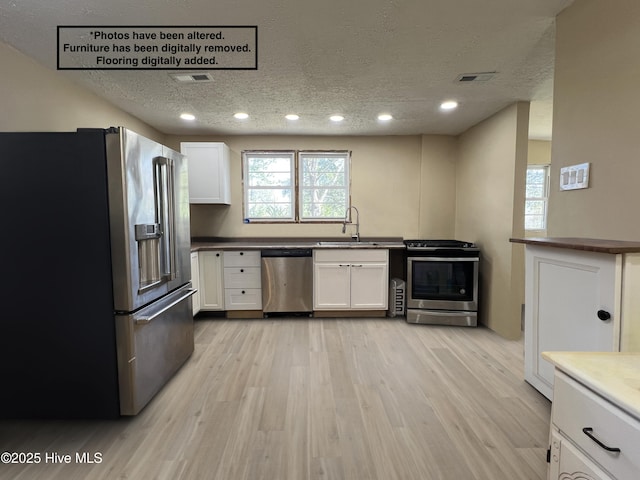 104 W Trent St, Trenton, NC 28585 - kitchen with stainless steel appliances, a textured ceiling, a sink, white cabinets, and light wood finished floors