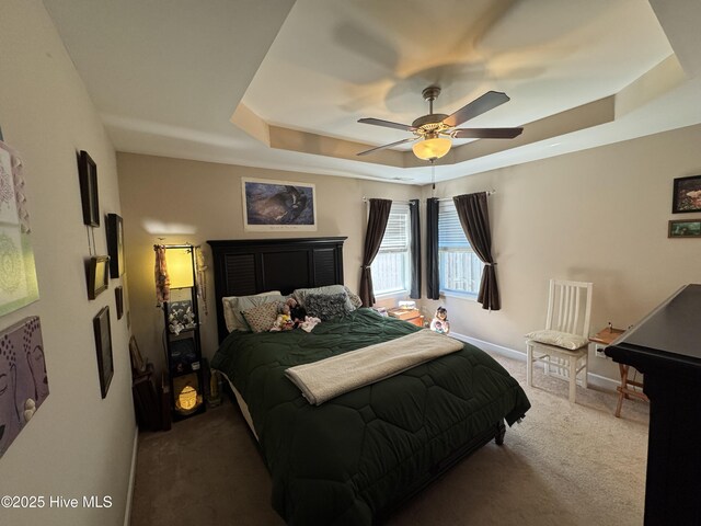 bedroom with carpet flooring, a ceiling fan, a tray ceiling, and baseboards