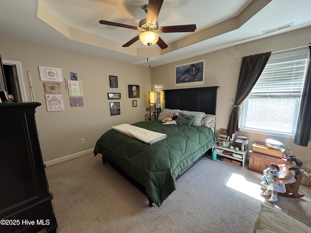 bedroom with baseboards, ceiling fan, carpet, and a tray ceiling