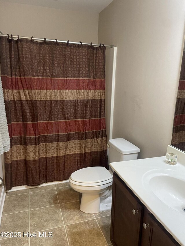 bathroom featuring vanity, tile patterned flooring, curtained shower, and toilet