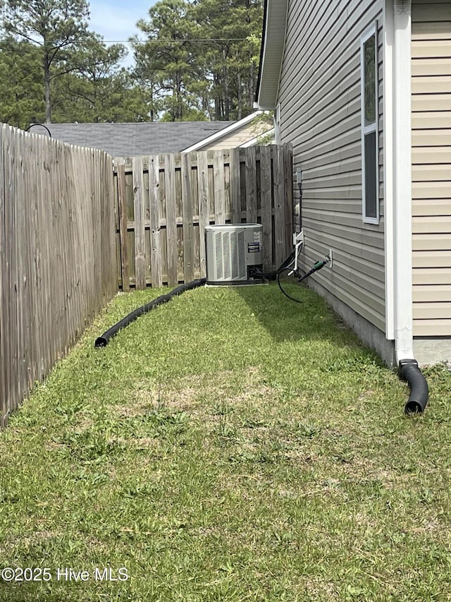 view of yard featuring central AC and fence