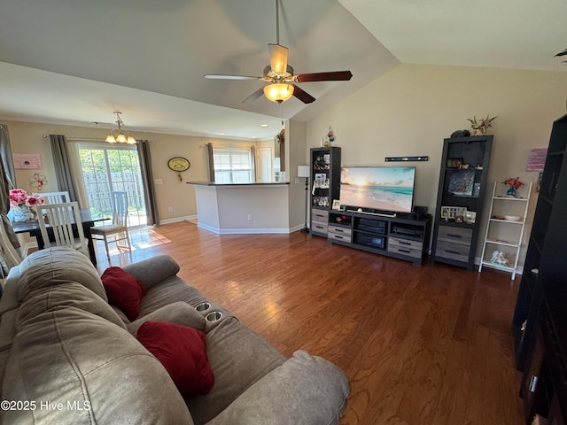 living area featuring wood finished floors, baseboards, ceiling fan with notable chandelier, and lofted ceiling