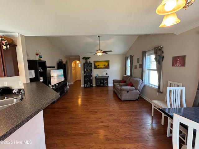 living area featuring ceiling fan, dark wood-style flooring, arched walkways, baseboards, and lofted ceiling