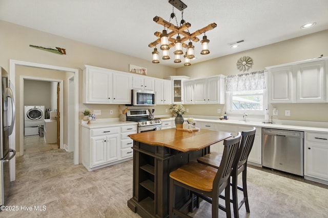 1744 Ocean Hwy S, Edenton, NC 27932 - kitchen with appliances with stainless steel finishes, white cabinetry, washer / clothes dryer, a sink, and a kitchen island