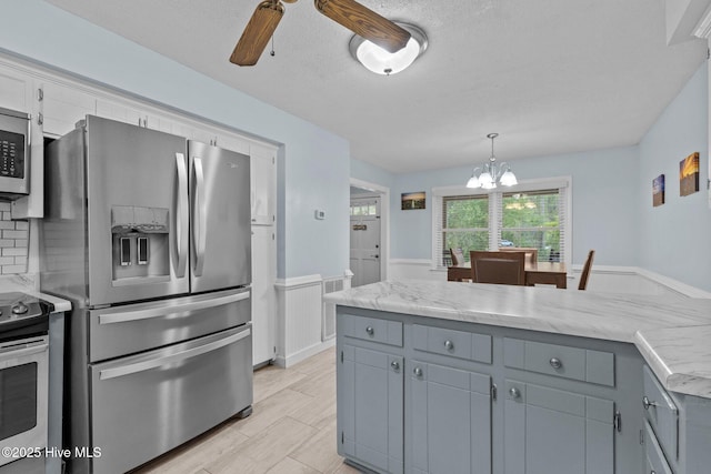 307 Little Rossie Rd, New Bern, NC 28560 - kitchen with stainless steel appliances, gray cabinets, a wainscoted wall, decorative light fixtures, and ceiling fan with notable chandelier