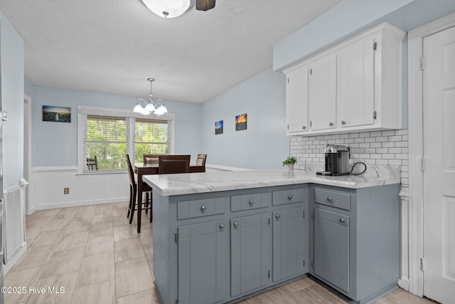 307 Little Rossie Rd, New Bern, NC 28560 - kitchen featuring a chandelier, wainscoting, a peninsula, gray cabinetry, and white cabinets