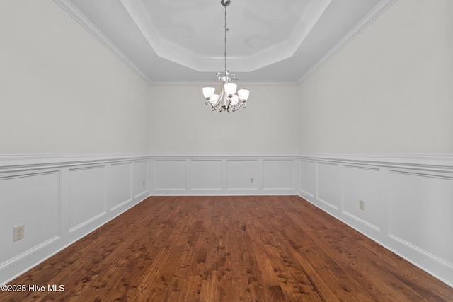 80 Whistling Straight Rd, Pinehurst, NC 28374 - spare room featuring a raised ceiling, a chandelier, dark wood-type flooring, crown molding, and a wainscoted wall