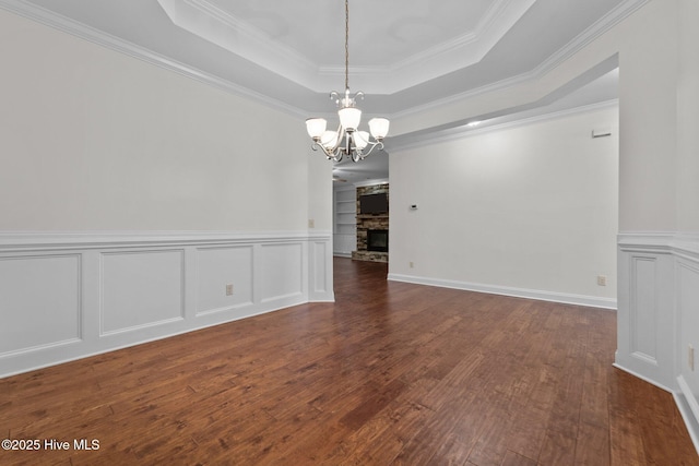 80 Whistling Straight Rd, Pinehurst, NC 28374 - spare room with a chandelier, a raised ceiling, dark wood-style flooring, crown molding, and a wainscoted wall