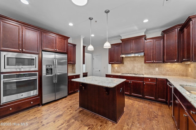 80 Whistling Straight Rd, Pinehurst, NC 28374 - kitchen with stainless steel appliances, ornamental molding, reddish brown cabinets, a center island, and backsplash