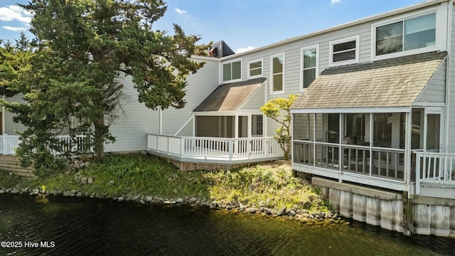 back of house featuring a water view and roof with shingles