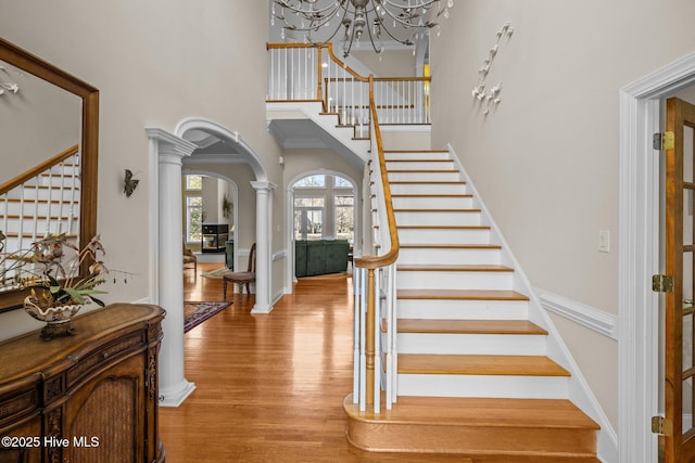 entrance foyer featuring arched walkways, a chandelier, stairway, and a towering ceiling