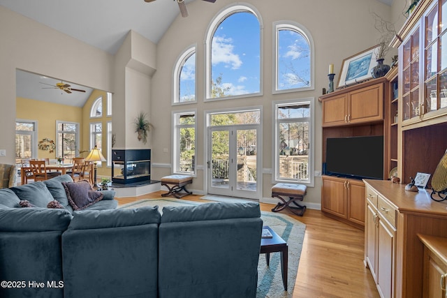 living area with light wood finished floors, ceiling fan, and high vaulted ceiling