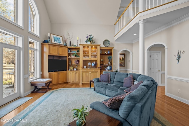 living room with light wood-type flooring, arched walkways, baseboards, and high vaulted ceiling