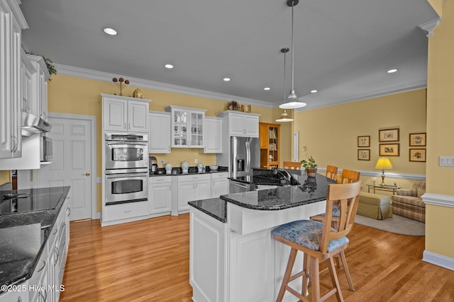 kitchen with crown molding, appliances with stainless steel finishes, a kitchen breakfast bar, and light wood-style floors