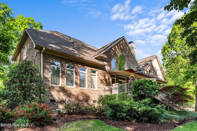 view of home's exterior featuring crawl space, a chimney, roof with shingles, stairway, and brick siding