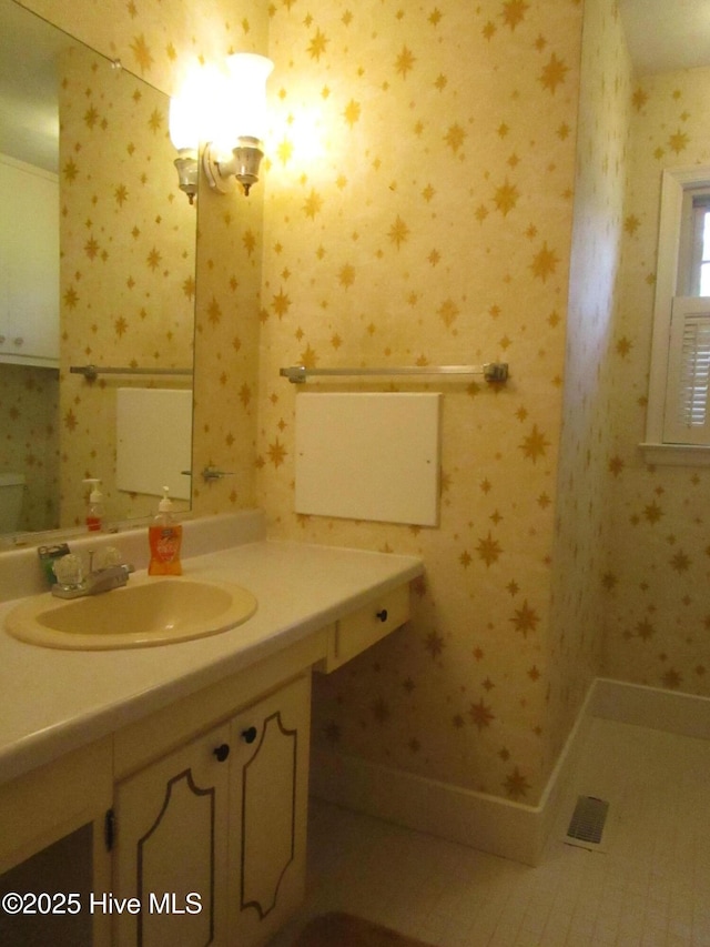 bathroom featuring vanity and wallpapered walls