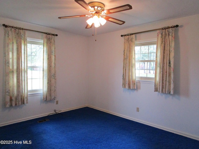 empty room featuring a healthy amount of sunlight, visible vents, baseboards, and ceiling fan