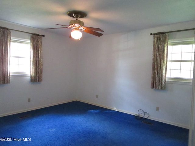 carpeted spare room with a healthy amount of sunlight, ceiling fan, and baseboards