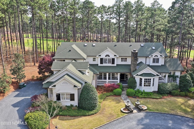 view of front of home with a front lawn, a shingled roof, driveway, and covered porch