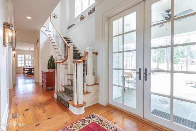 entryway featuring light wood-type flooring, french doors, stairs, visible vents, and ceiling fan with notable chandelier