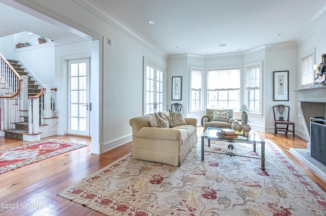living area with hardwood / wood-style floors, a fireplace with raised hearth, plenty of natural light, and stairs