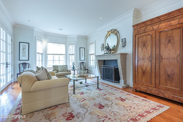 living area featuring recessed lighting, a fireplace with raised hearth, ornamental molding, and wood finished floors