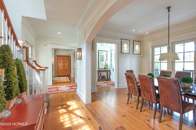 dining room with arched walkways, crown molding, light wood finished floors, recessed lighting, and stairs