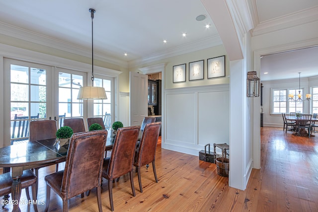 dining space featuring a decorative wall, ornamental molding, and light wood finished floors