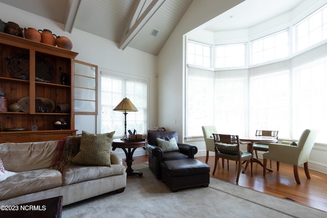 living room featuring high vaulted ceiling, light wood finished floors, and beam ceiling