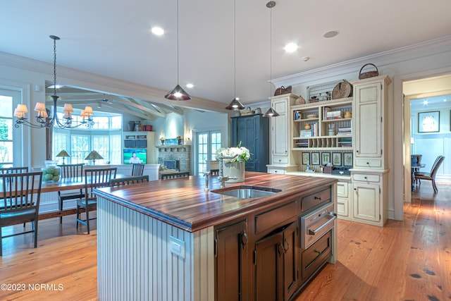 kitchen featuring a sink, a fireplace, crown molding, butcher block counters, and a warming drawer