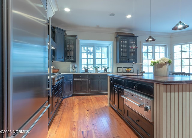 kitchen featuring a wealth of natural light, built in refrigerator, light wood-style flooring, and crown molding