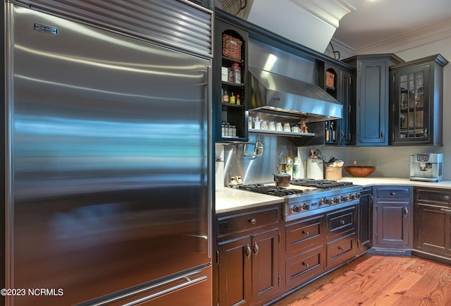 kitchen with glass insert cabinets, light wood-style flooring, ornamental molding, light countertops, and stainless steel appliances