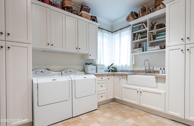 clothes washing area with stone finish floor, washer and clothes dryer, a sink, and cabinet space