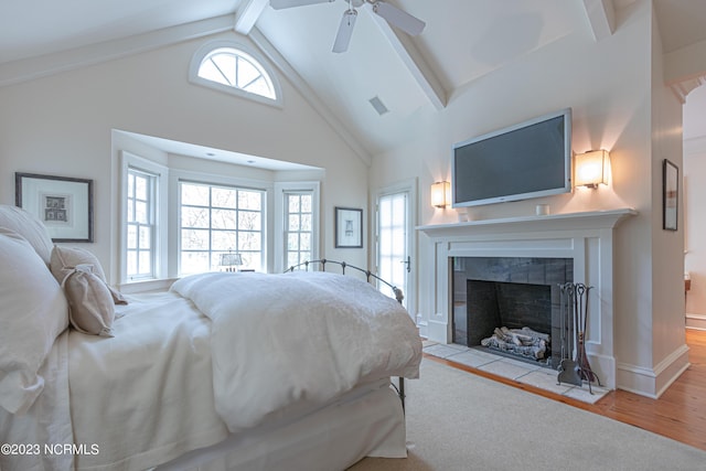 bedroom with beamed ceiling, high vaulted ceiling, visible vents, wood finished floors, and a tile fireplace