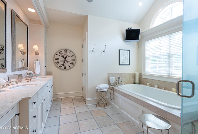 bathroom featuring a garden tub, vanity, vaulted ceiling, recessed lighting, and baseboards