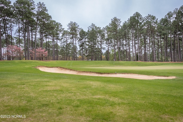 surrounding community with view of golf course and a lawn