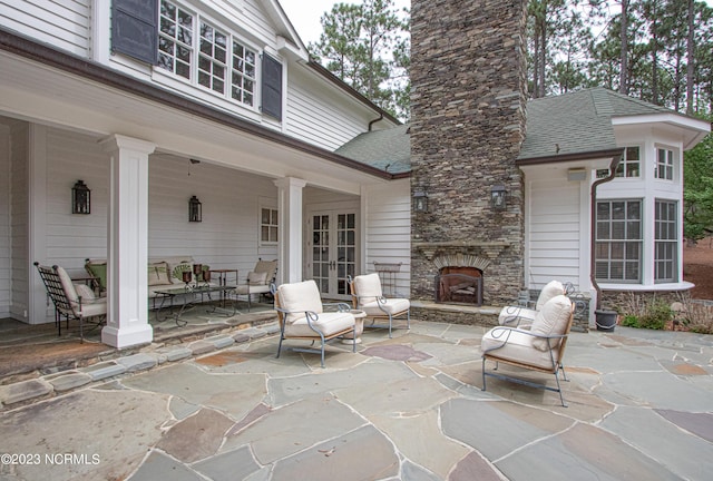 view of patio / terrace featuring french doors and an outdoor stone fireplace