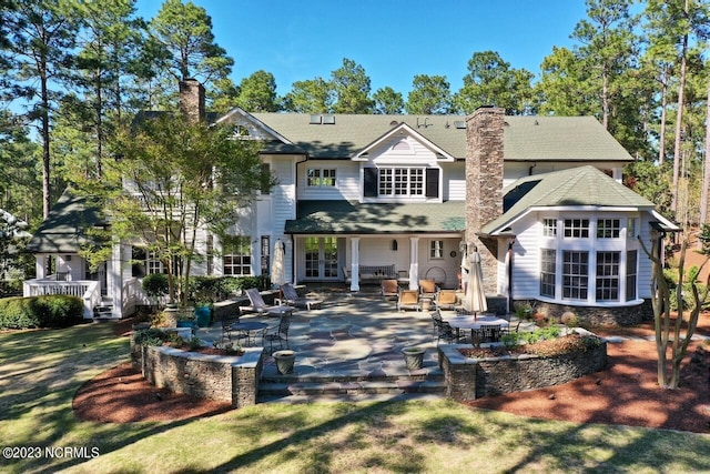 rear view of house with french doors, a chimney, and a patio area