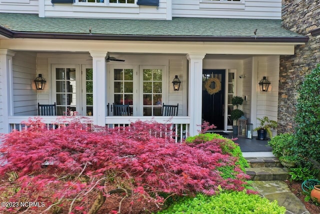 view of exterior entry featuring a shingled roof and covered porch