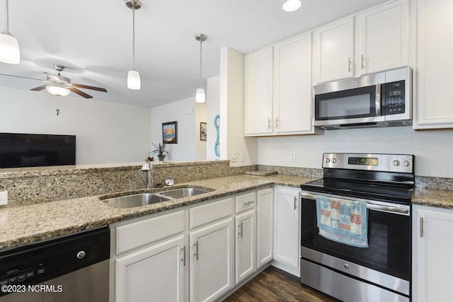 kitchen featuring light stone counters, stainless steel appliances, white cabinets, and a sink