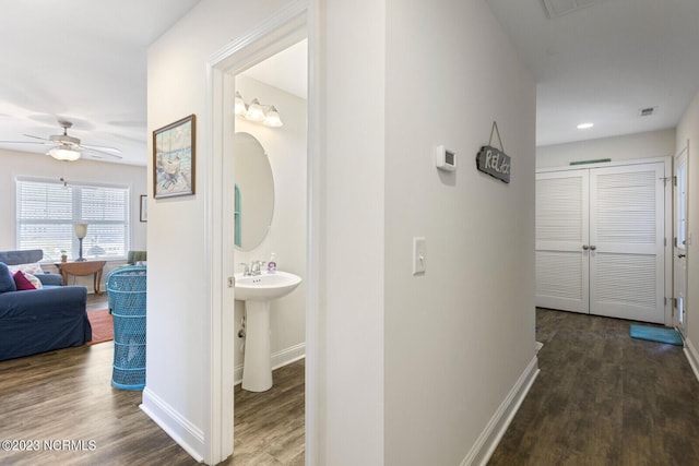 hall featuring visible vents, wood finished floors, and baseboards