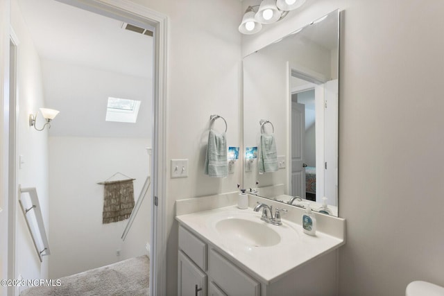half bathroom with vanity, visible vents, and a skylight