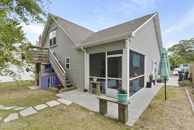 rear view of property with a yard, a sunroom, a deck, stairway, and roof with shingles