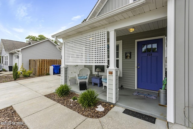 entrance to property featuring board and batten siding, covered porch, and fence