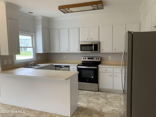 kitchen with appliances with stainless steel finishes, a sink, a peninsula, light countertops, and white cabinetry