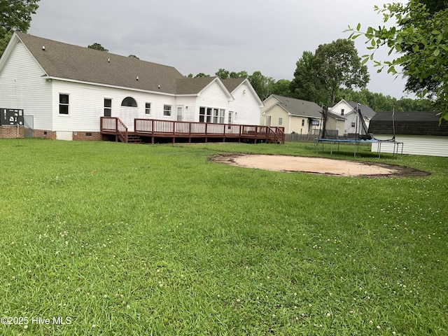 view of grassy yard featuring a trampoline and a deck