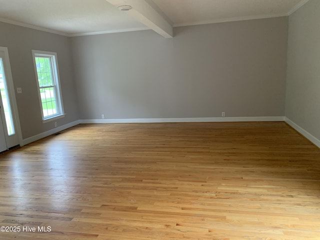 spare room featuring wood finished floors, crown molding, and baseboards